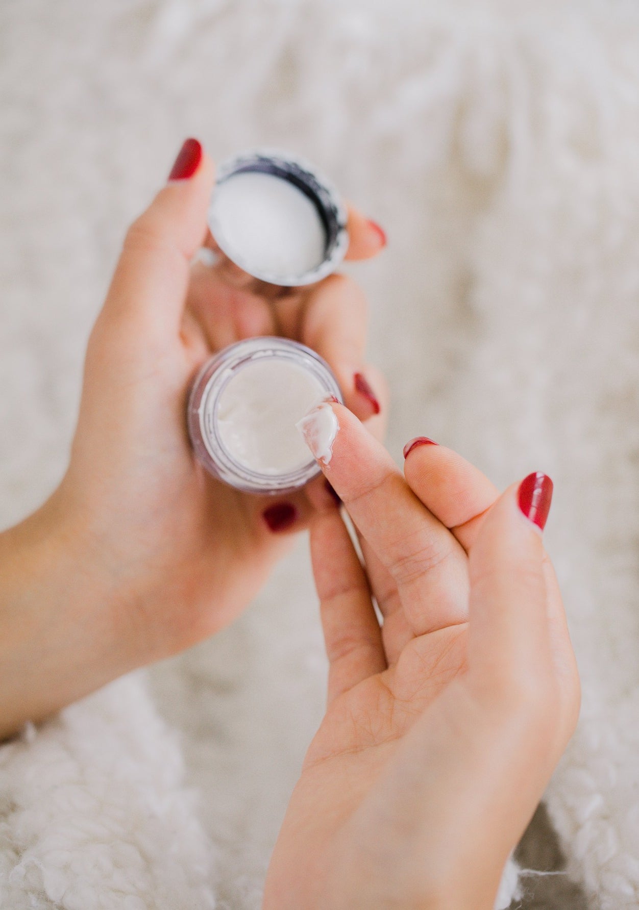 Hands holding a small cosmetics jar
